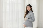 Happy,Pregnant,Woman,Turtleneck,Sweatshirt,Standing,In,Front,Of,Windows
